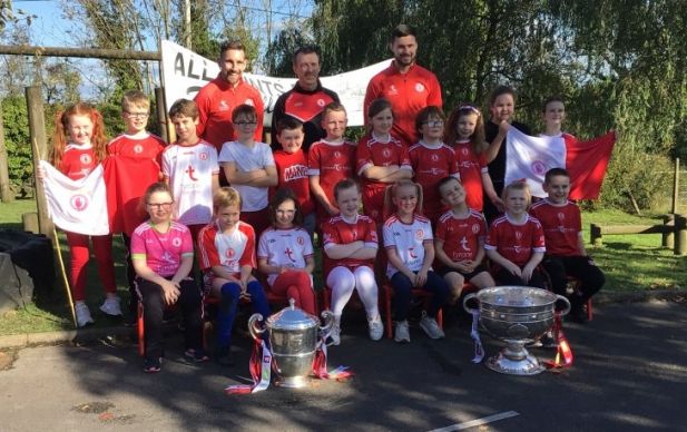 Tyrone players Niall Sludden & Peter Teague bring Sam Maguire and the Anglo Celt Cup to meet pupils from All Saints' PS.